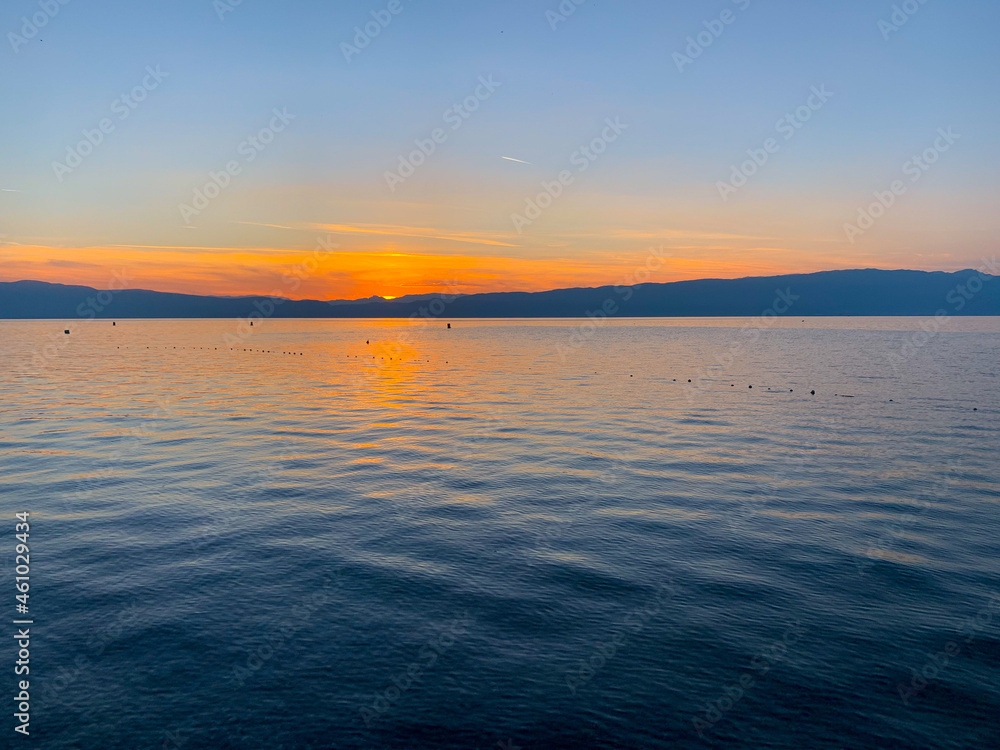 Beautiful sunset on the lake, natural colors, silhouette of the mountains background, deep blue color
