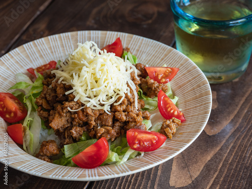 沖縄料理のタコライス。スパイシーに炒めた挽き肉とレタスとトマトとチーズをご飯のトッピングした料理。 photo