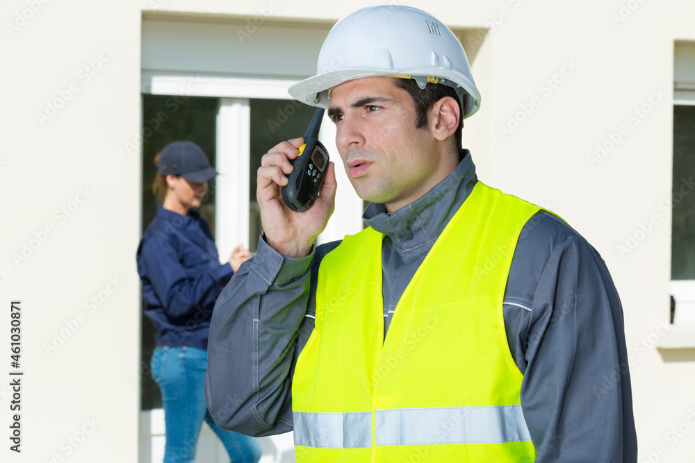 man wearing reflective vest using walkie-talkie outside property man wearing reflective vest using walkie-talkie outside property
