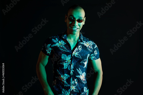 Neon light studio close-up portrait of attractive male model in sunglasses and Hawaiian shirt. portrait photo of a dark-skinned handsome guy.