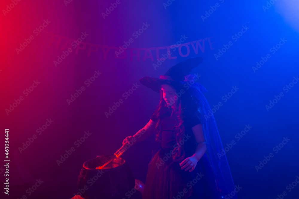 Child girl witch preparing a potion in the cauldron at halloween holidays. Copy space. Child girl witch preparing a potion in the cauldron at halloween holidays. Copy space.