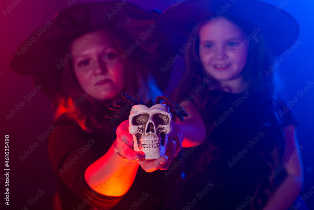 Two halloween witches making magic with scull in halloween night. Magic, holidays and mystic concept. Two halloween witches making magic with scull in halloween night. Magic, holidays and mystic concept.