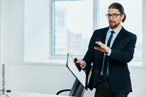 The man in a suit in the office gestures with his hands boss