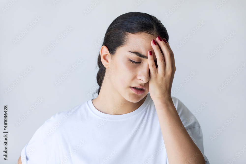 Portrait of an annoyed woman suffering from a headache isolated over gray background
