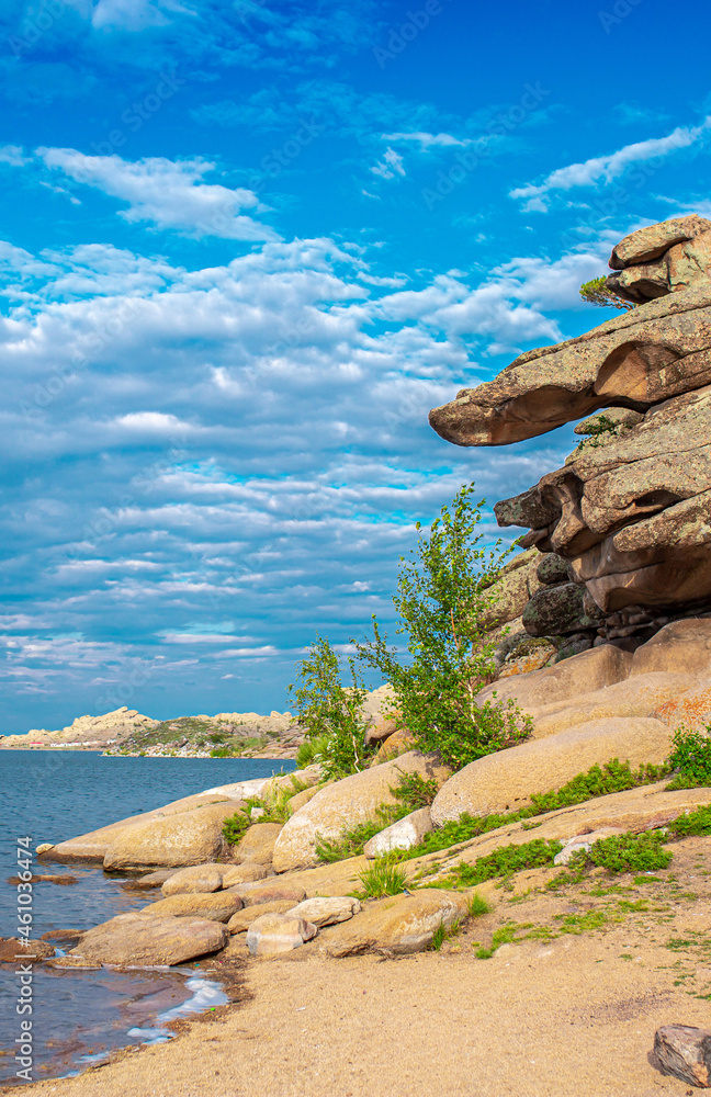 Beautiful nature of the lake and rocky mountains. Unusual landscape of nature. Trees among the rocks against the sky with clouds. Beautiful nature of the lake and rocky mountains. Unusual landscape of nature. Trees among the rocks against the sky with clouds.