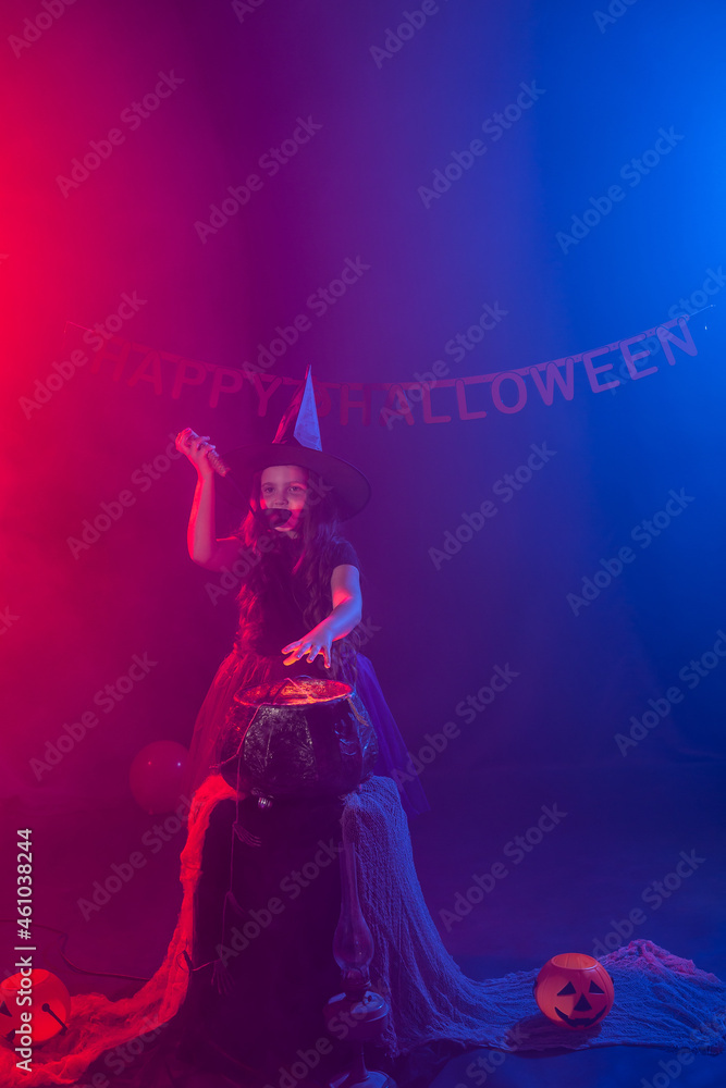 Fototapeta premium Little witch child cooking potion in the cauldron on Halloween.