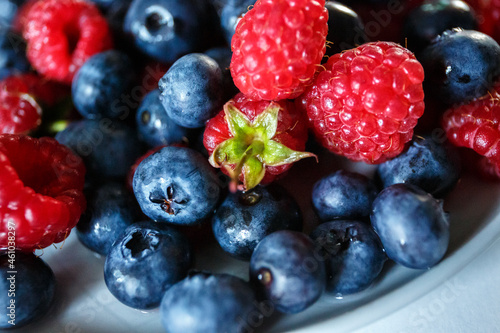Delicious juicy ripe wild berries raspberries and blueberries in colorant. Washed berries for breakfast