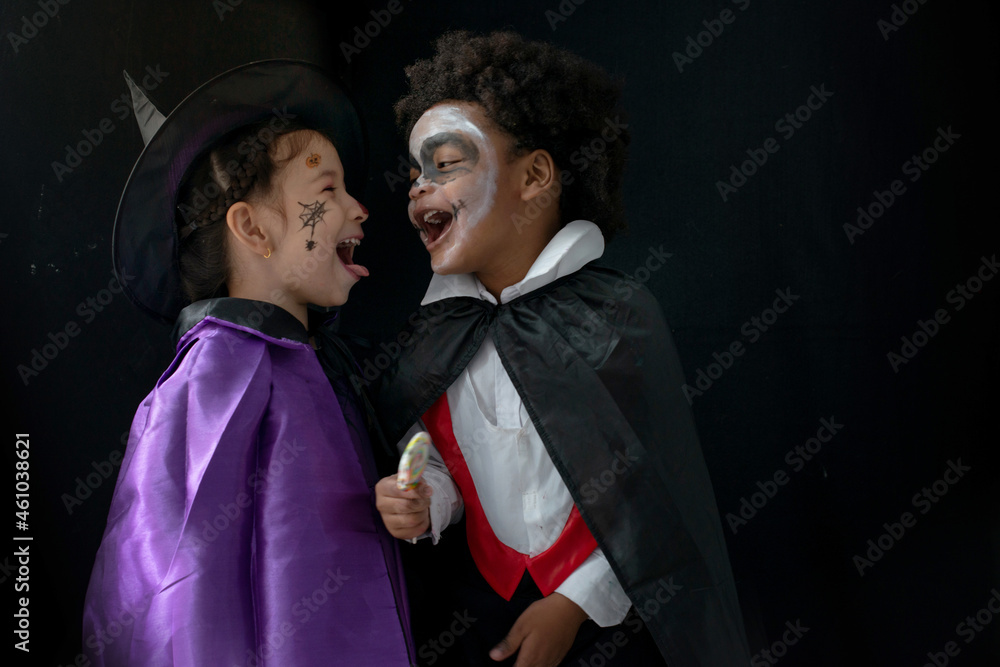 Cute little Dracula boy and witch girl for Halloween celebration, making scary gesture on black background, Happy Halloween concept