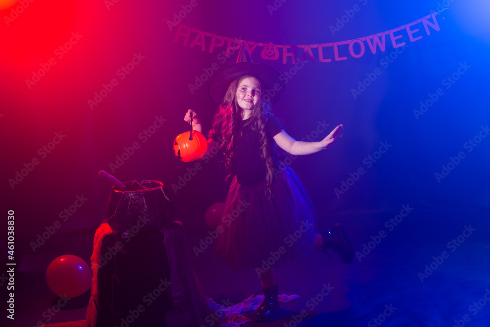 Little girl holds pumpkin jack on Halloween holiday. Kid girl wear witch costume. Fantasy, fairy tale and masquerade concept.