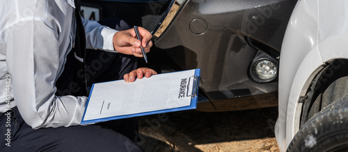Fotografie Insurance Agent Inspecting assessed Damaged Car checking and signing on report i