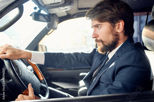 bearded man in a suit in a car a trip to work rich