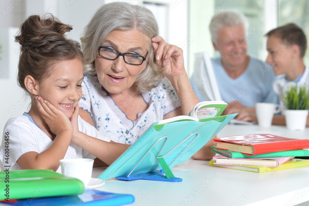 Fototapeta premium Grandmother with cute little girl doing homework together