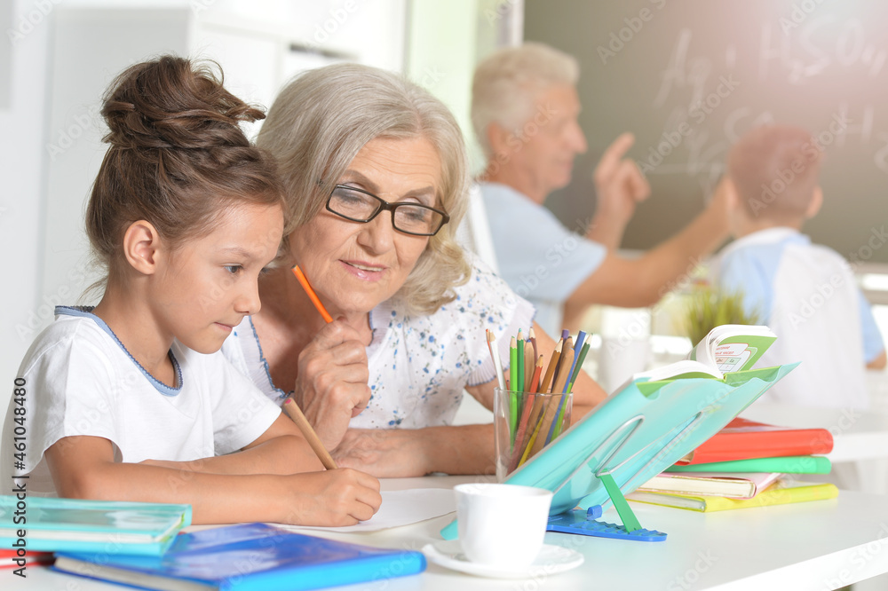 Grandmother with cute little girl doing homework together Grandmother with cute little girl doing homework together
