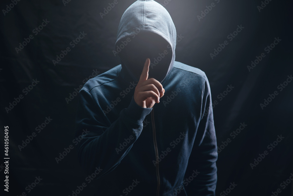 the hacker in the hood makes a silence gesture - obrazy, fototapety, plakaty 
