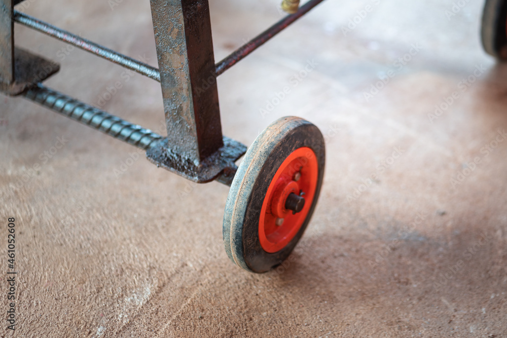 Fototapeta premium Small rubber wheel of the handyman trolley cart which is used for store some hand tool and service equipment at the garage. Vehicle part object, close-up and selective focus.