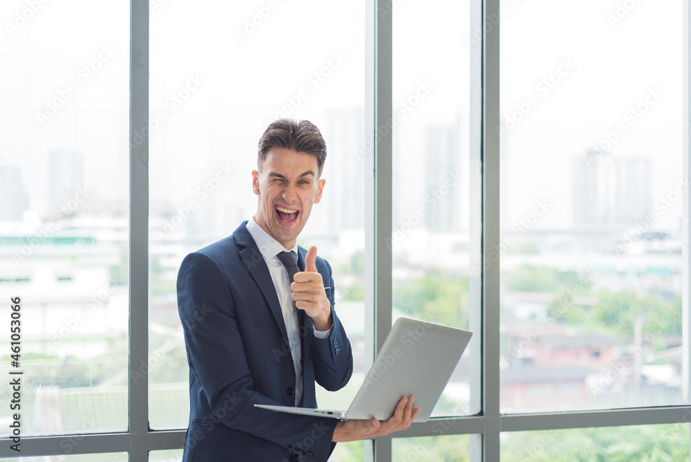 Portrait of adult smart business man in suit outfit standing and using laptop in modern workplace Portrait of adult smart business man in suit outfit standing and using laptop in modern workplace