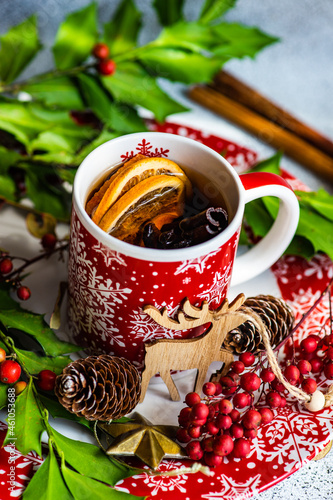Cup of spiced mulled tea on a table with holly and spices photo
