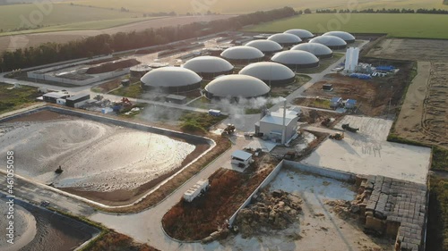 Biogas plant surrounded by nature. Modern storage tanks on biogas farm on field. Renewable energy from biomass. Aerial view. Energy source. photo