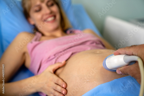 Pregnant young woman at gynecologist having her baby examined with ultrasound device.