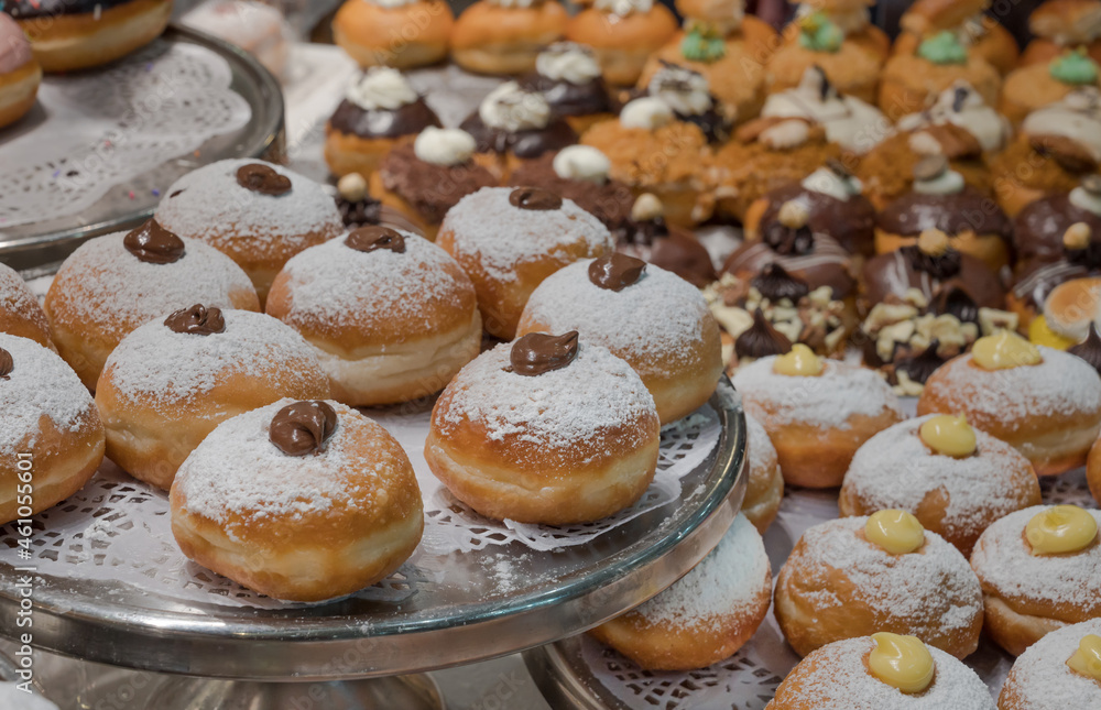 Fresh donuts with chocolate at the bakery display for Hanukkah celebration. Selective focus. Fresh donuts with chocolate at the bakery display for Hanukkah celebration. Selective focus.