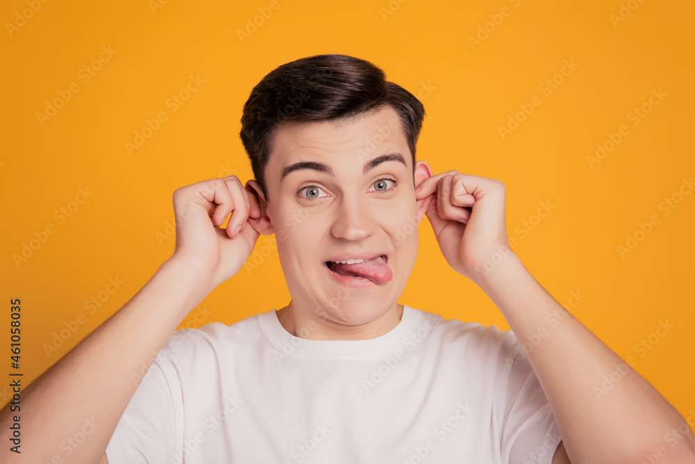 Portrait of funny childish crazy guy have fun grimacing mocking on yellow background Portrait of funny childish crazy guy have fun grimacing mocking on yellow background