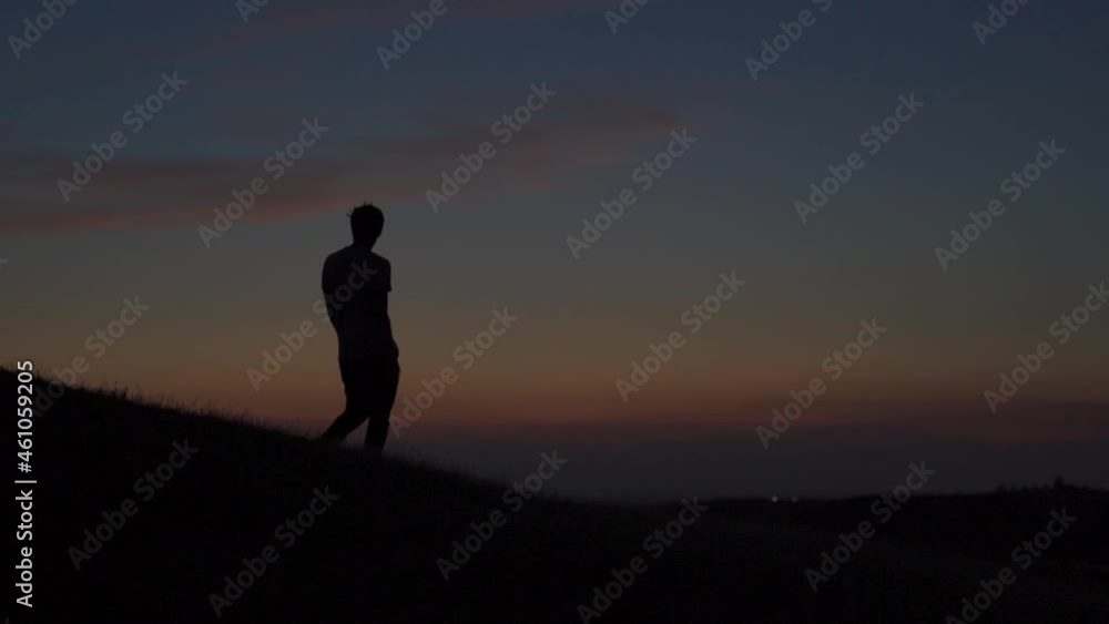 Silhouette of an Indian man walking in front of the orange clouds after the sunset during the blue hour. Lonely man walks in front of the orange clouds. Loneliness background. Silhouette of an Indian man walking in front of the orange clouds after the sunset during the blue hour. Lonely man walks in front of the orange clouds. Loneliness background.