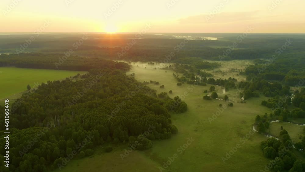 Aerial drone flies over winding river flows through green meadow and forest. Fog over water surface, early morning. Flying high above of waterway before sunrise. Misty dawn, idyllic green valley Aerial drone flies over winding river flows through green meadow and forest. Fog over water surface, early morning. Flying high above of waterway before sunrise. Misty dawn, idyllic green valley