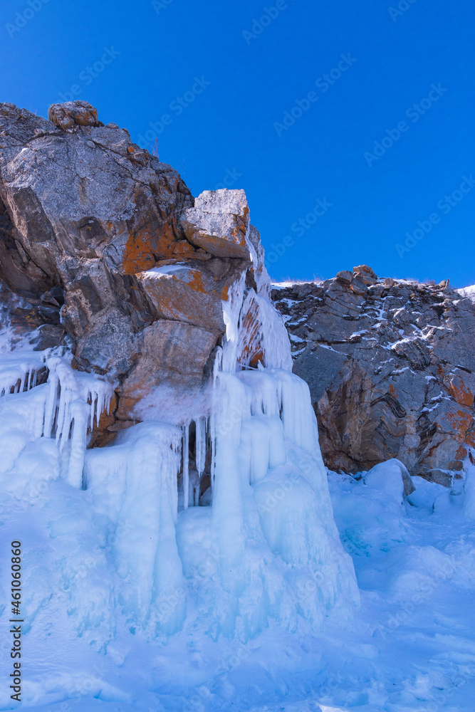 Blue ice waterfall on Ogoy Island in the Maloye More Strait on Lake Baikal on a sunny winter day. Siberia, Russia.