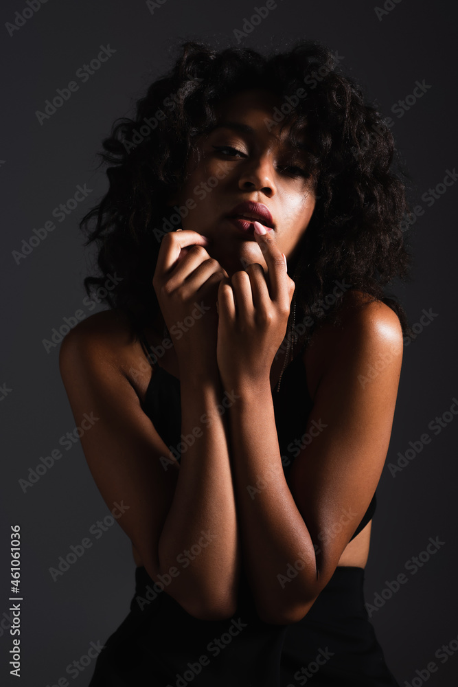 sexy african american woman looking at camera while touching lips isolated on black sexy african american woman looking at camera while touching lips isolated on black