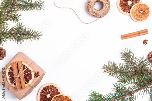 Christmas composition with handmade kraft paper gift box, dried citrus slices, cinnamon, anise, pine cones and fir tree branches, top view copy space