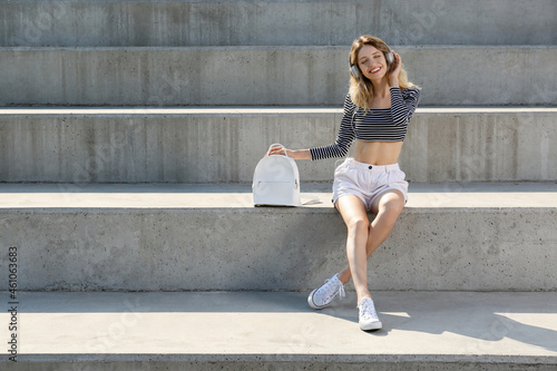 Young woman with stylish backpack on stairs outdoors. Space for text