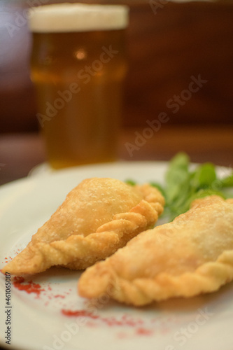 plate menu with Argentine empanadas with beer on a table in a night bar
