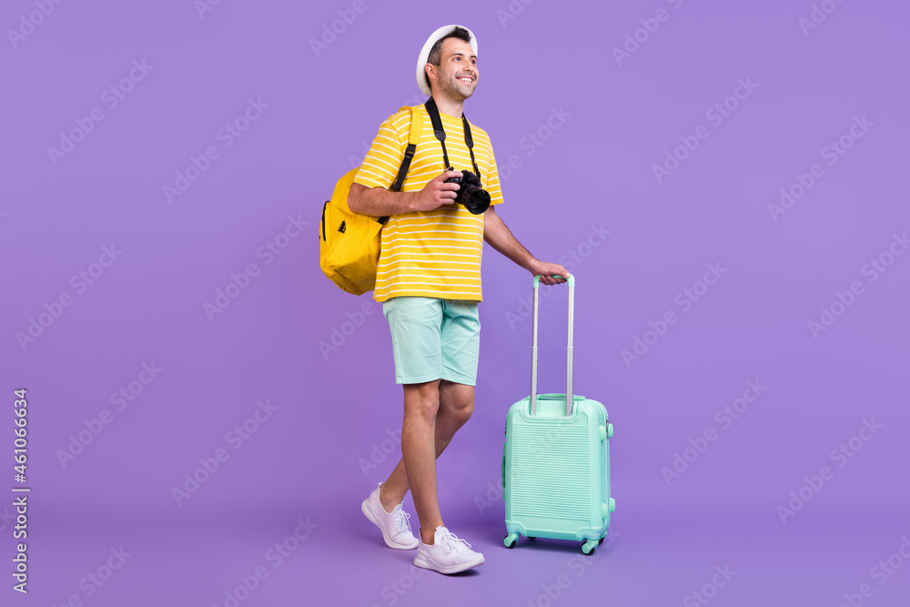 Full length photo of young man look go empty space vacation wear yellow striped t-shirt bag camera isolated on violet color background Full length photo of young man look go empty space vacation wear yellow striped t-shirt bag camera isolated on violet color background