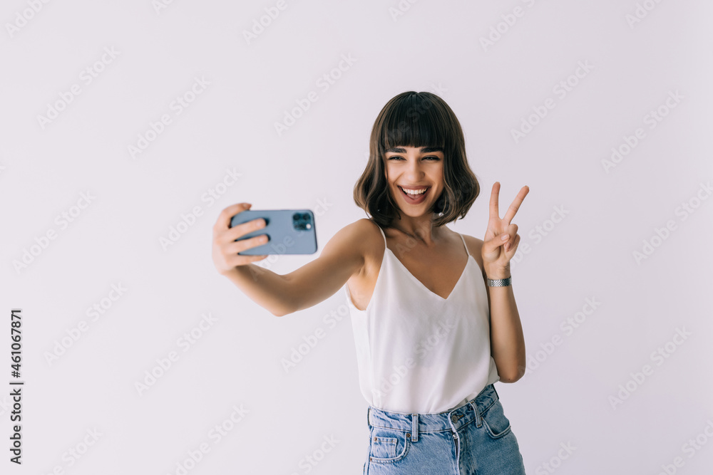 Portrait of a young attractive woman making selfie photo on smartphone on a white background Portrait of a young attractive woman making selfie photo on smartphone on a white background