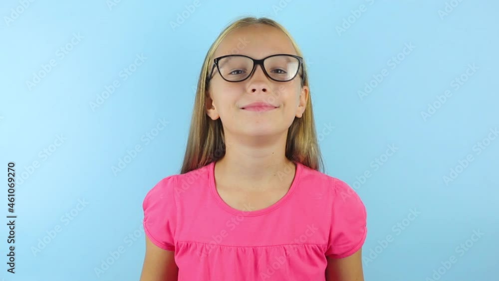 girl in a good mood on a blue background puts on glasses for correcting vision. girl in a good mood on a blue background puts on glasses for correcting vision.