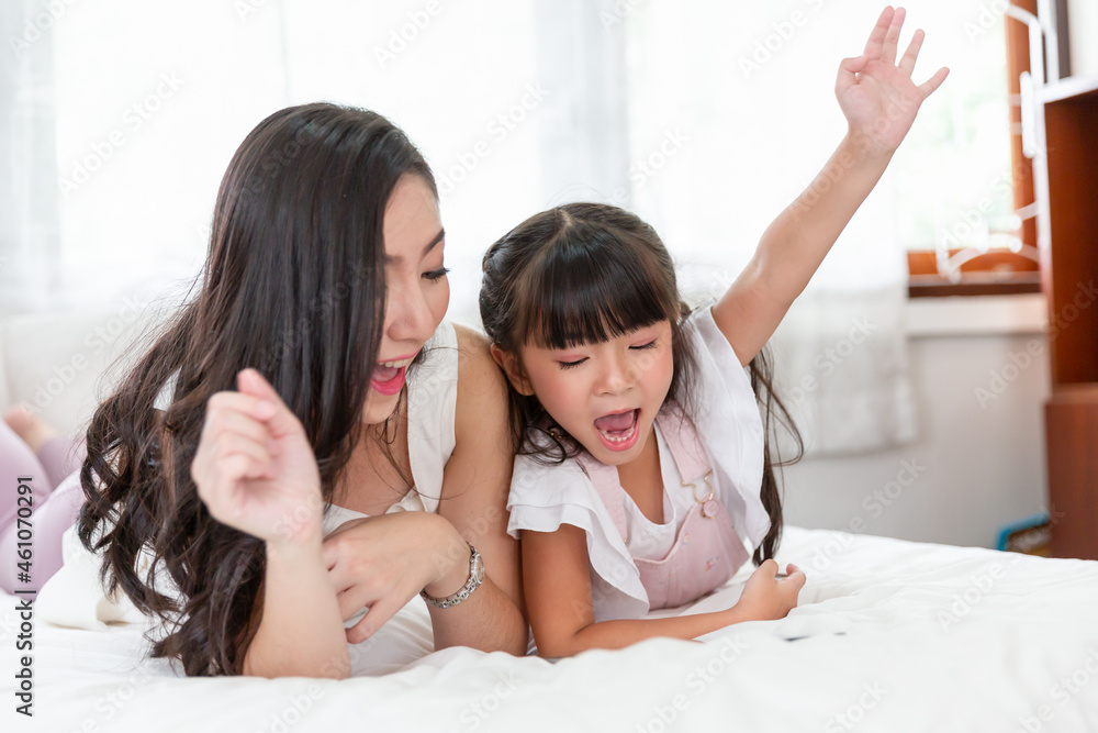 Young asian mother and little daughter using tablet technology internet online together at home. Mom and adorable child are having fun with tablet.