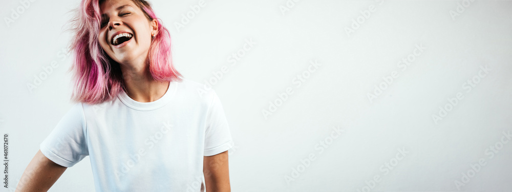 Positive laughs plus size model with white blank t-shirt and pink hear, empty grunge wall background - obrazy, fototapety, plakaty 