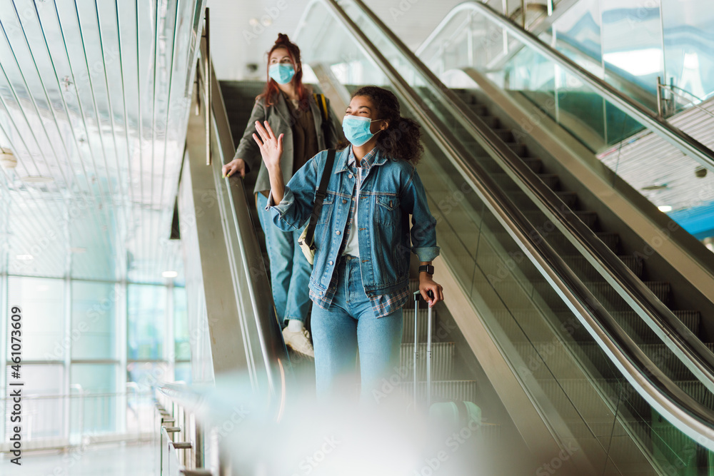 Multiracial two women in face masks going to escalator at train station