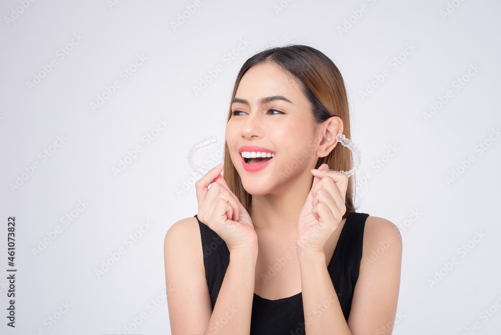 Young smiling woman holding invisalign braces in studio, dental healthcare and Orthodontic concept Young smiling woman holding invisalign braces in studio, dental healthcare and Orthodontic concept