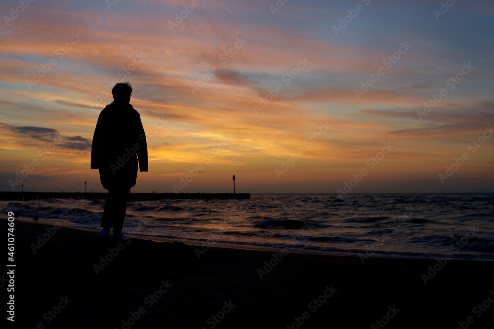 Silhouette of a vacationer walking on the beach in Kolobrzeg on the Polish Baltic coast after sunset 