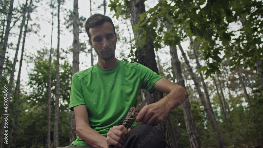 A male survivalist in the forest is preparing to hunt. Ties a knife to a stick. Making a spear A male survivalist in the forest is preparing to hunt. Ties a knife to a stick. Making a spear