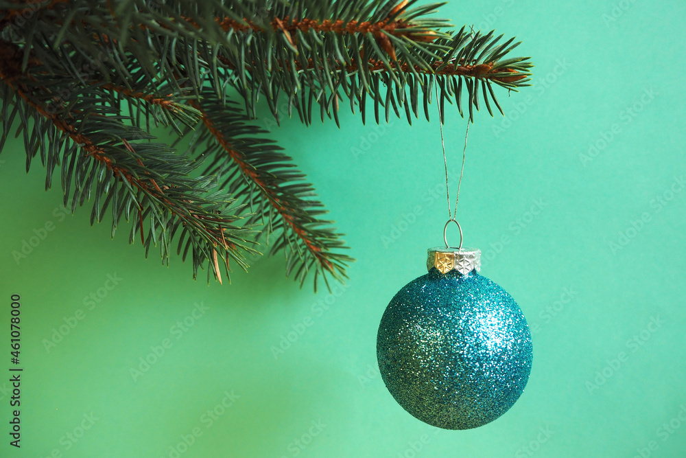 round shiny christmas ball hanging on a christmas tree on a green background. holidays round shiny christmas ball hanging on a christmas tree on a green background. holidays