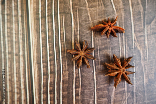three brown anise stars lie on a wooden table. top view