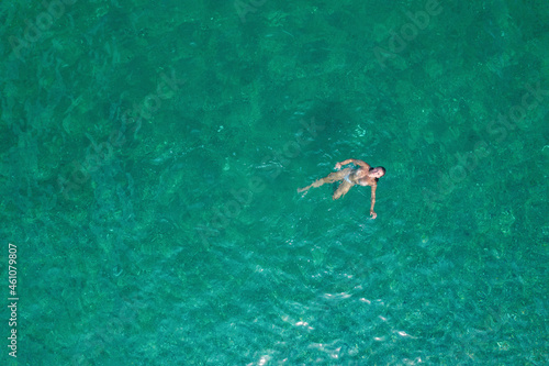 Young nude beautiful  sexy woman with naked breast taking off swimsuit standing in sea  ocean water. Summer. View from above. Top view  copter