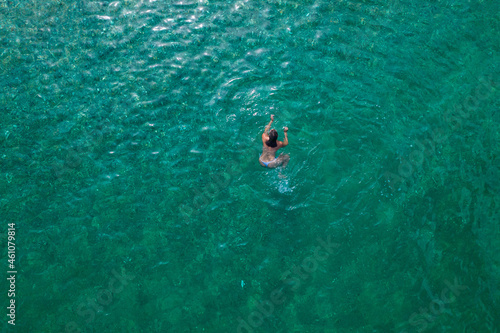 Young woman in a swimsuit swimming in sea water on the beach. View from above. Top, drone view © flowertiare