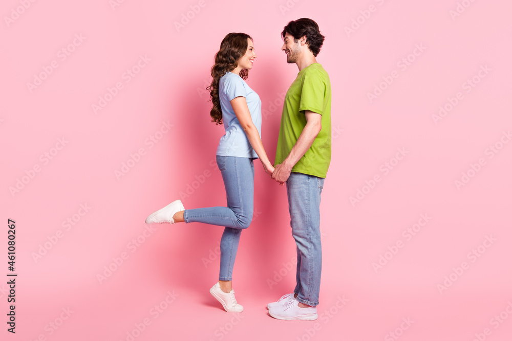 Full length photo of cheerful happy couple hold hands good mood smile date isolated on pink color background Full length photo of cheerful happy couple hold hands good mood smile date isolated on pink color background