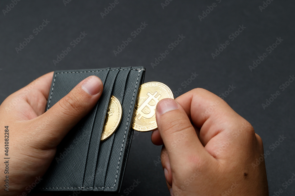 Fototapeta premium A person holds Bitcoin coins. A businessman puts bitcoin gold coins into a wallet. Bitcoin purchase concept. Bitcoin and wallet. Bitcoin Conservation. Cryptocurrency. Close-up. Virtual money