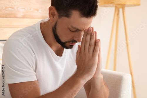 Religious man with clasped hands praying indoors © New Africa