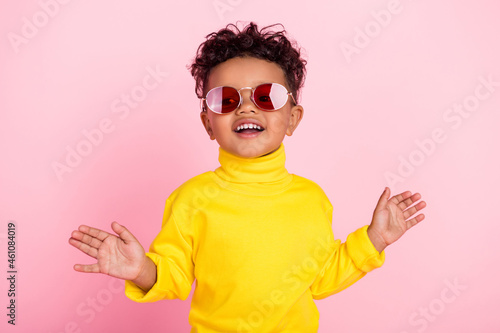 Photo of satisfied carefree dark skin pupil toothy beaming raise hands palms isolated on pink color background