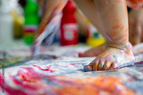 Children painting images with water color on the paper and making prints by hands and foots.